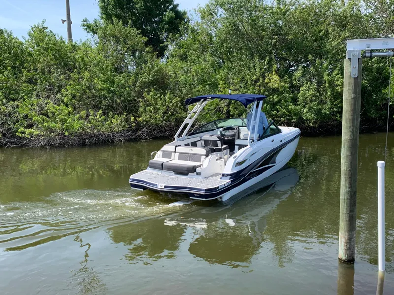 Slide: The Image of 2021 Monterey M6 boat cruising on a calm river near lush greenery. - 5