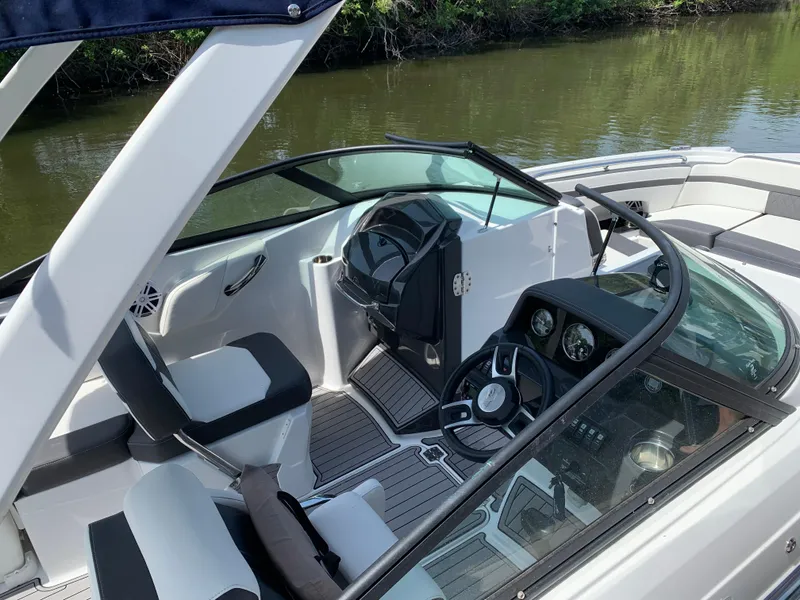 Slide: The Image of 2021 Monterey M6 boat interior with steering wheel and seating, on calm water. - 8