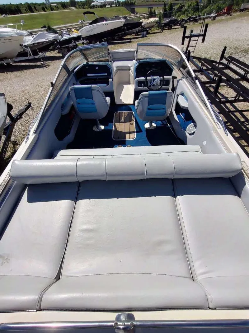 Slide: The Image of 1988 Sea Ray 230 Bow Rider Select with blue and white interior, docked outdoors. - 3