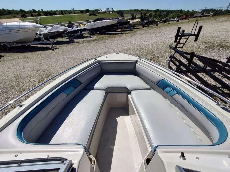 Slide: The Image of 1988 Sea Ray 230 Bow Rider Select with spacious seating, parked in a boatyard. - 7