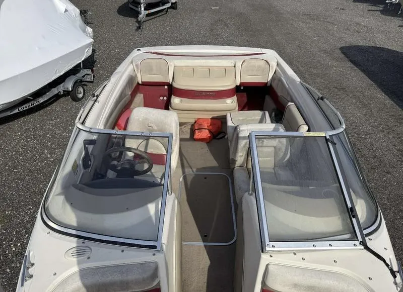 Slide: The Image of 1999 Glastron 185 boat interior with red and beige seating, parked on asphalt. - 4