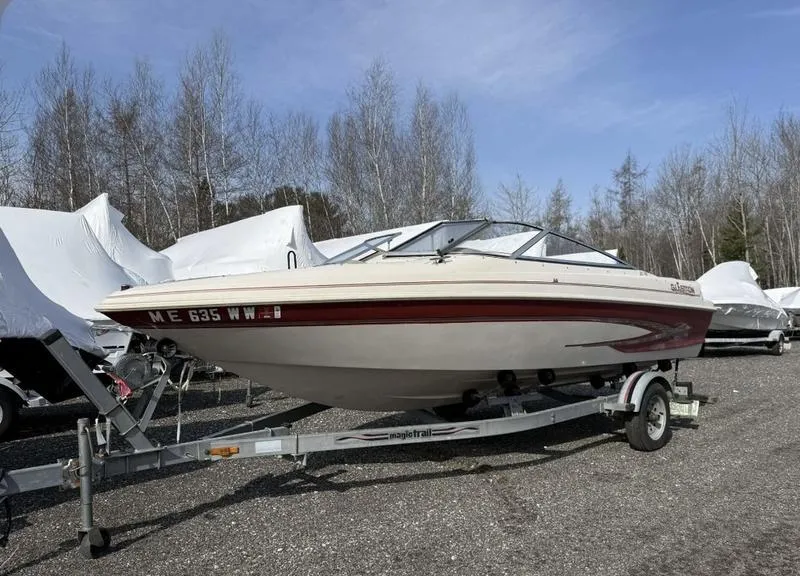 Slide: The Image of 1999 Glastron 185 boat on trailer, parked outdoors with trees in the background. - 6