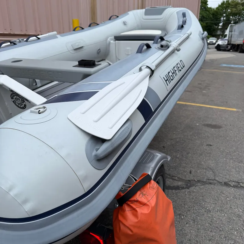 Slide: The Image of 2024 Highfield CL340 inflatable boat with oars on a trailer in a parking lot. - 10