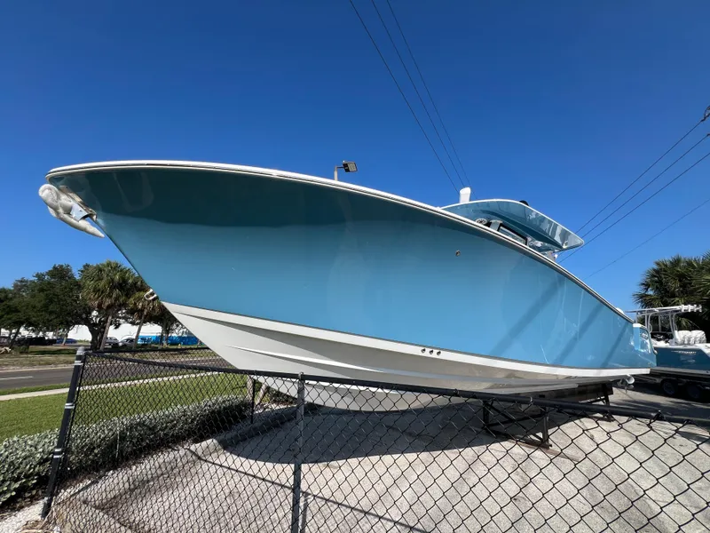 Slide: The Image of 2025 Sportsman 352 Open boat in blue, displayed outdoors behind a fence. - 2
