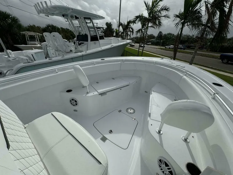Slide: The Image of 2025 Sportsman 232 Open boat interior with seating and storage, surrounded by palm trees. - 10
