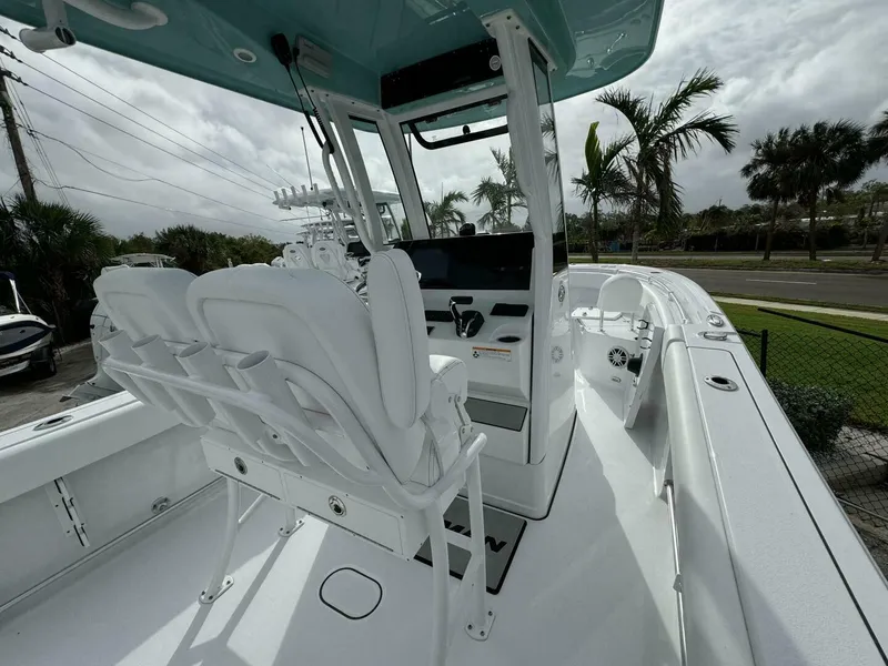 Slide: The Image of 2025 Sportsman 232 Open boat interior with white seating and console, surrounded by palm trees. - 5