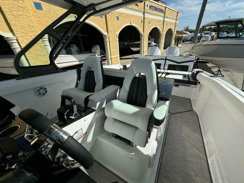 Slide: The Image of 2025 Monterey 30 ELITE boat interior with modern seating and steering, docked near a yellow building. - 10