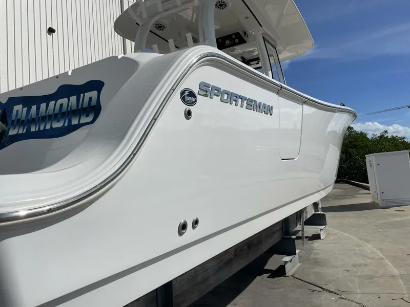 Slide: The Image of 2021 Sportsman 302 OPEN boat, sleek white design, docked outdoors under blue sky. - 6