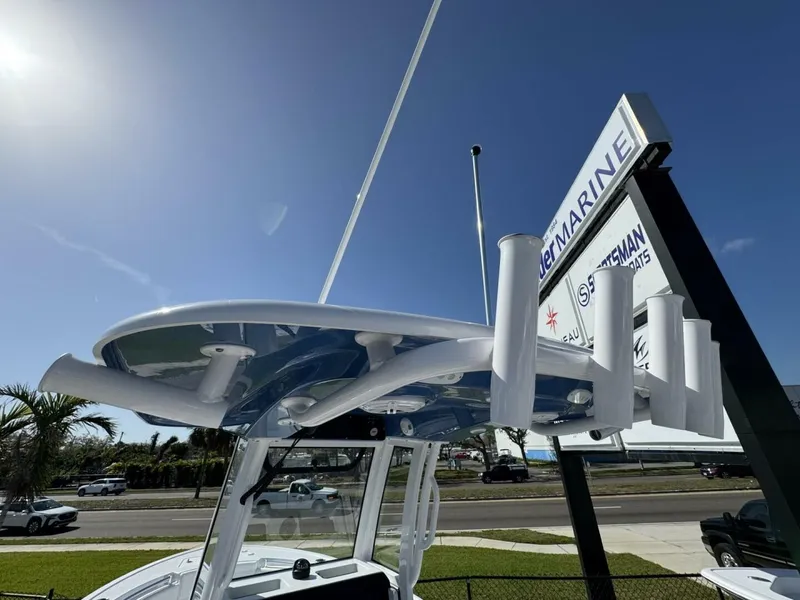 Slide: The Image of 2025 Sportsman 212 Open boat with rod holders, displayed outdoors under a clear blue sky. - 15