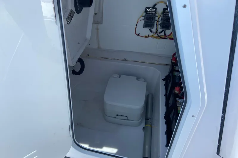Slide: The Image of 2025 Sportsman Open 212 Center Console storage compartment with portable toilet and battery setup. - 27