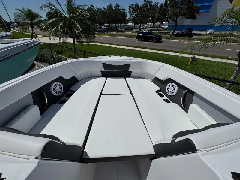 Slide: The Image of 2024 Monterey M225 boat interior with white seating and speakers, parked near palm trees. - 11
