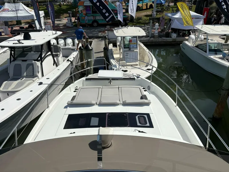 Slide: The Image of 2025 Jeanneau 1295 FLY yacht displayed at a boat show, docked alongside other vessels. - 6