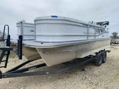 Slide: The Image of 2025 SunCatcher Select 322SS pontoon boat on a trailer, parked on gravel. - 1