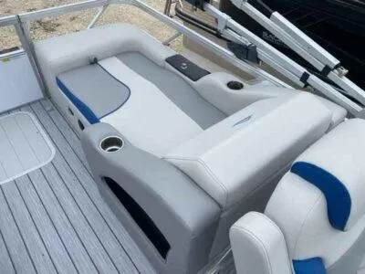 Slide: The Image of 2025 SunCatcher Select 322SS boat interior with gray and blue seating, cup holders, and sleek design. - 6