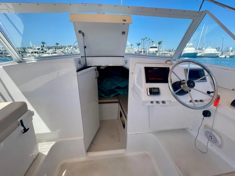 Slide: The Image of 1966 Bertram 25 Moppie boat interior with steering wheel, open cabin door, and marina view. - 13