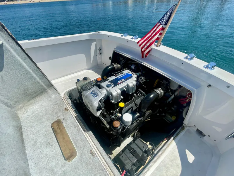 Slide: The Image of 1966 Bertram 25 Moppie boat engine compartment with American flag, docked on clear water. - 18