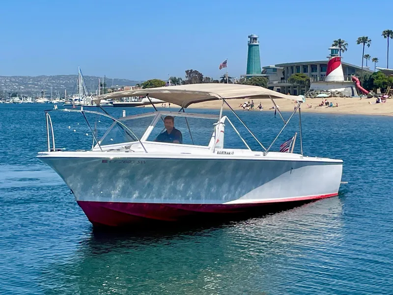 Slide: The Image of 1966 Bertram 25 Moppie boat cruising near a scenic beach with lighthouse in background. - 2
