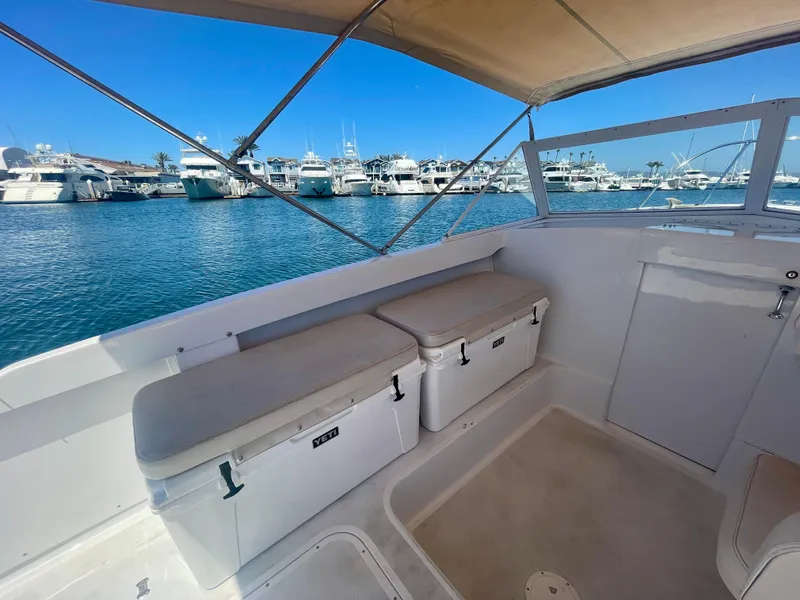 Slide: The Image of 1966 Bertram 25 Moppie boat interior with seating, docked in a marina under clear blue skies. - 7