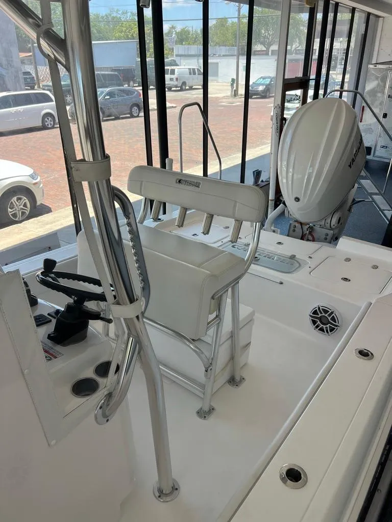 Slide: The Image of 2025 Contender 23 Bay boat interior with seating and motor, displayed in a showroom. - 11