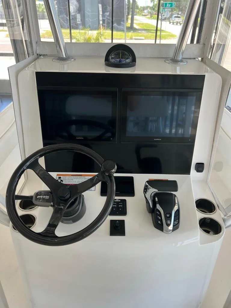 Slide: The Image of 2025 Contender 23 Bay boat console with steering wheel, dual screens, and controls. - 4