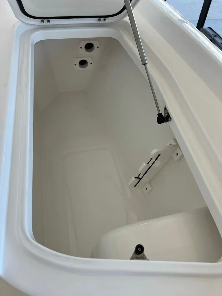 Slide: The Image of 2025 Contender 23 Bay boat storage compartment, open lid, white interior, hydraulic support. - 9