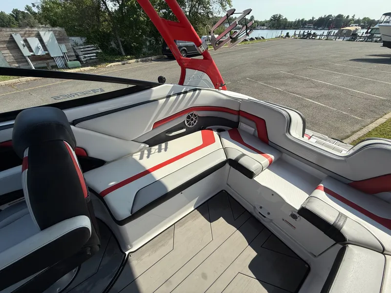 Slide: The Image of 2019 Yamaha Boats 242X E-Series interior with red and white seating, dockside view. - 13
