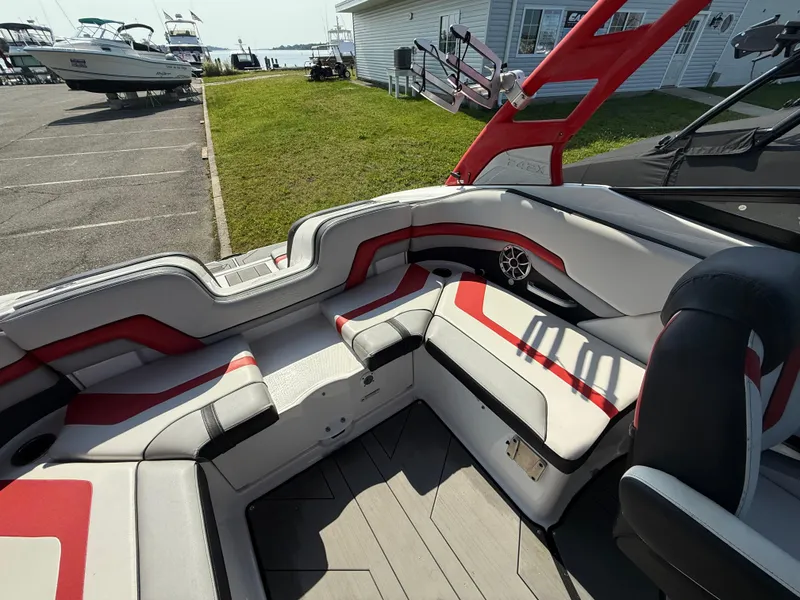 Slide: The Image of 2019 Yamaha Boats 242X E-Series interior with red and white seating, docked near a marina. - 14