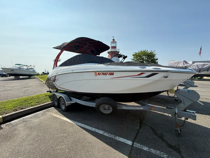 Slide: The Image of 2019 Yamaha Boats 242X E-Series on trailer, parked outdoors, with cover and canopy. - 2
