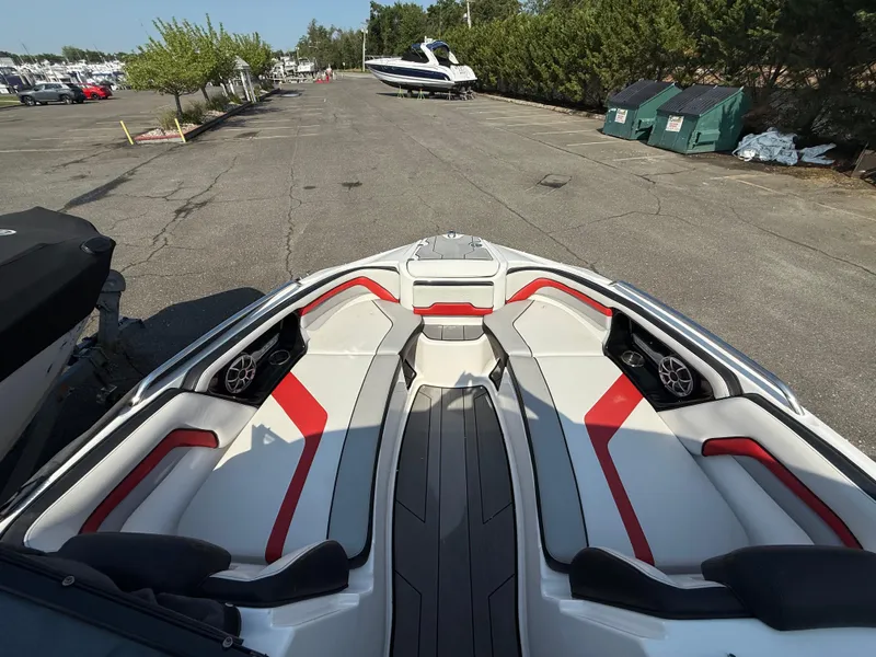 Slide: The Image of 2019 Yamaha Boats 242X E-Series interior with red accents, parked in a marina. - 21