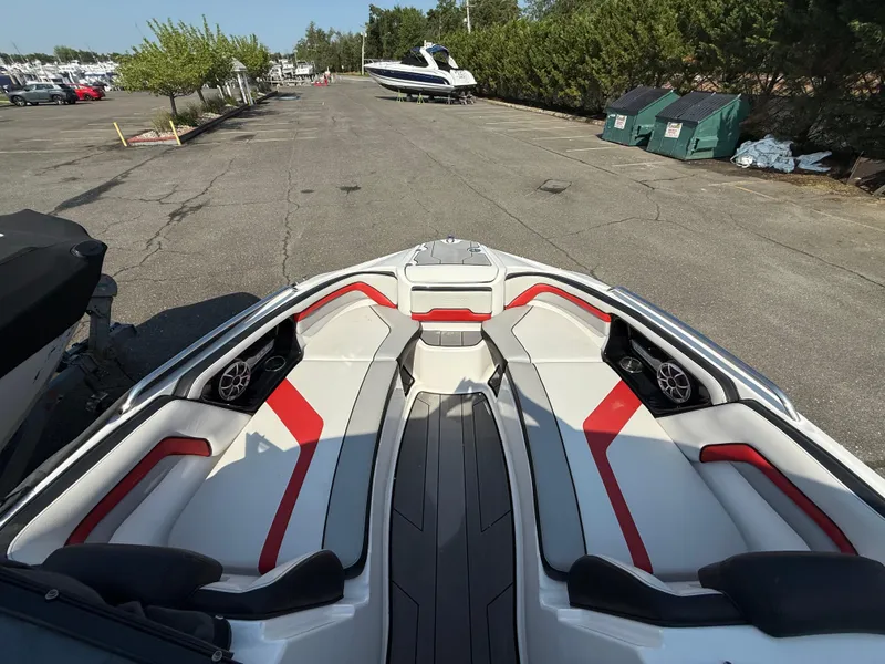 Slide: The Image of 2019 Yamaha Boats 242X E-Series interior with red and white seating in a parking lot. - 22
