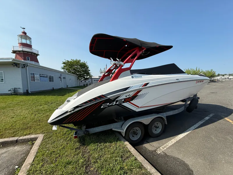 Slide: The Image of 2019 Yamaha Boats 242X E-Series on trailer near lighthouse and building. - 3