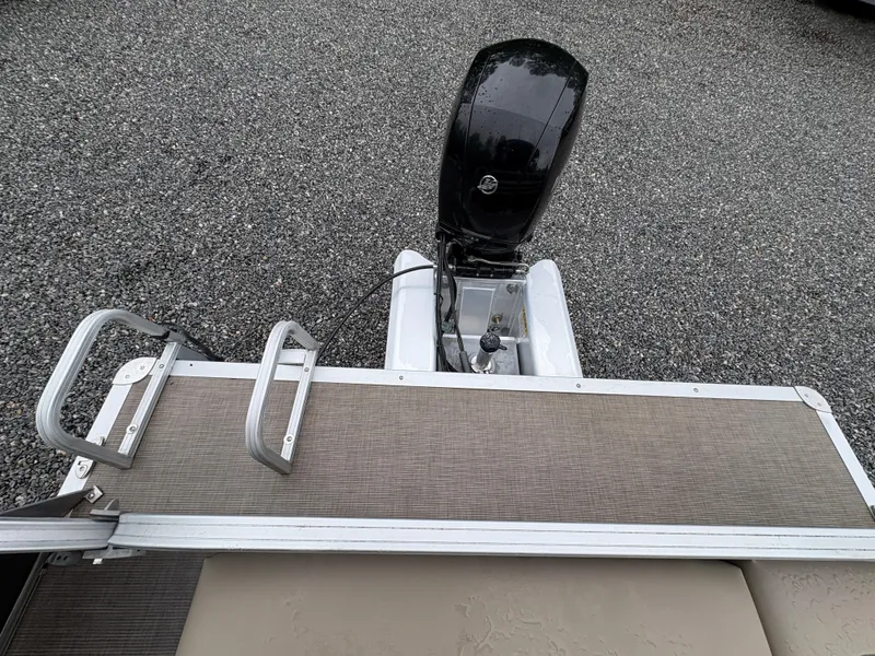 Slide: The Image of 2022 Sun Tracker PARTY BARGE with outboard motor and swim ladder on gravel surface. - 14