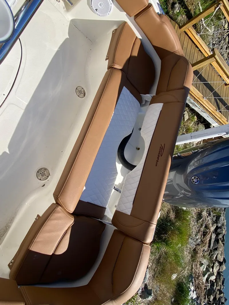 Slide: The Image of 2025 Pioneer 202 Islander boat interior with brown and white seating, dockside view. - 9