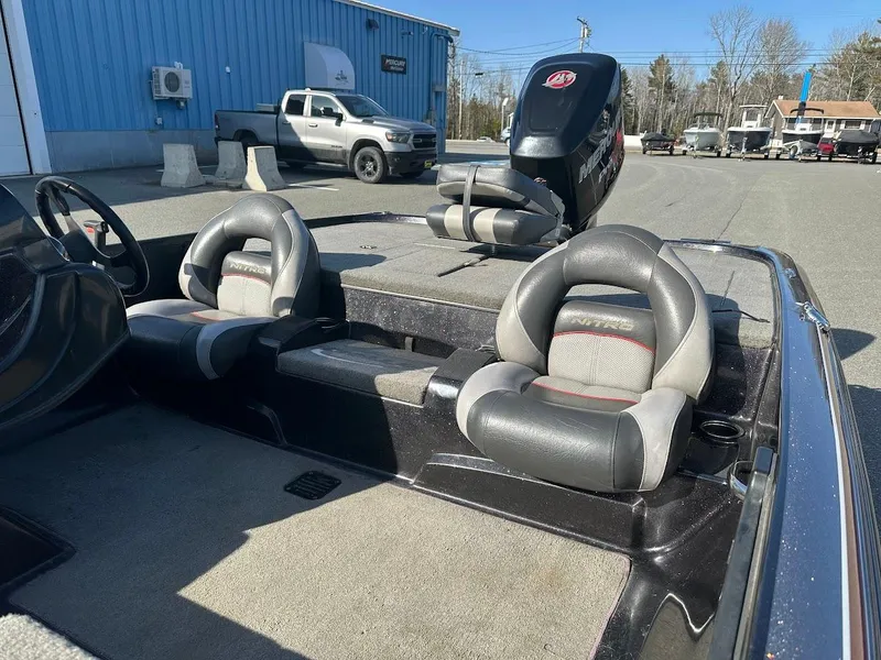 Slide: The Image of 2013 Nitro Z7 18' boat interior with dual seats and motor, parked outdoors. - 4