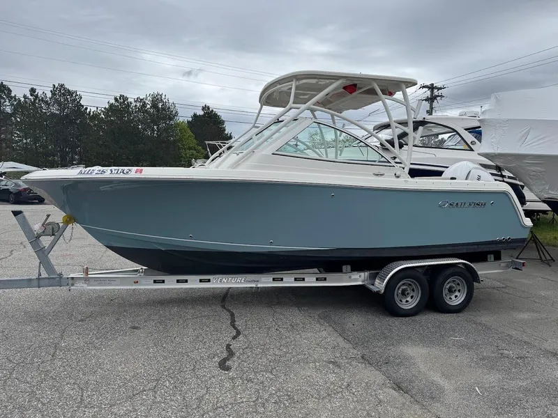 Slide: The Image of 2023 Sailfish 245 DC boat on trailer, parked outdoors, overcast sky. - 0