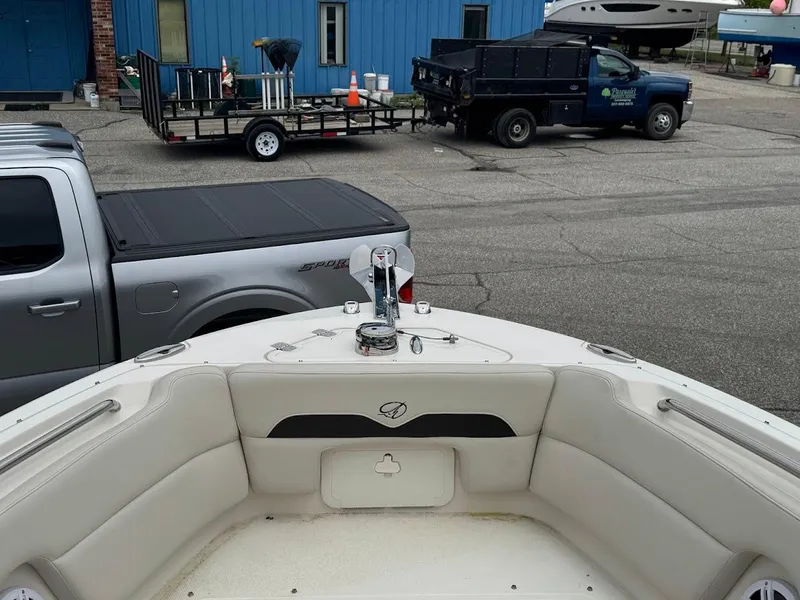 Slide: The Image of 2023 Sailfish 245 DC boat interior with docked vehicles in the background. - 8