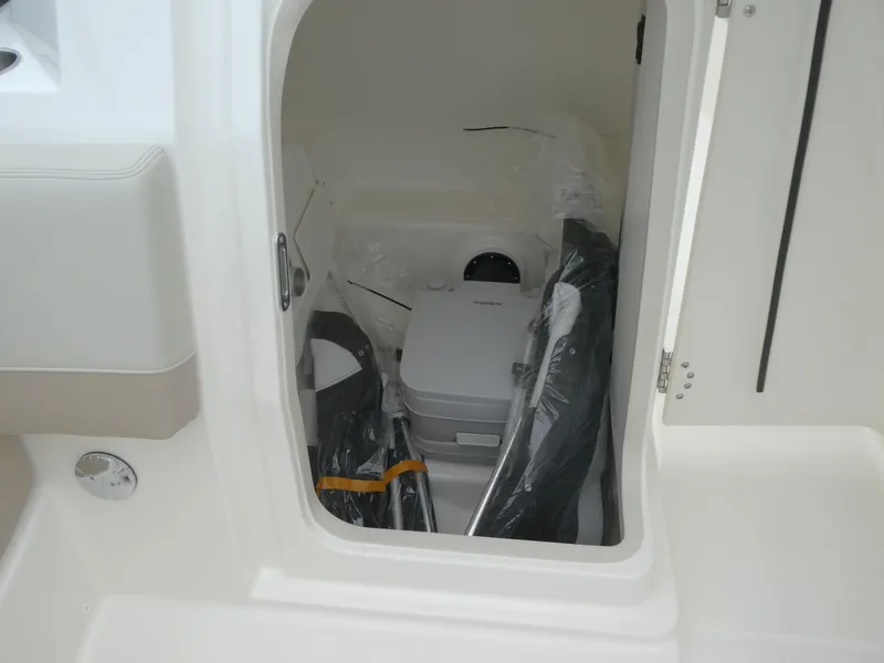 Slide: The Image of 2025 Boston Whaler 210 Vantage storage compartment with portable toilet and accessories. - 17