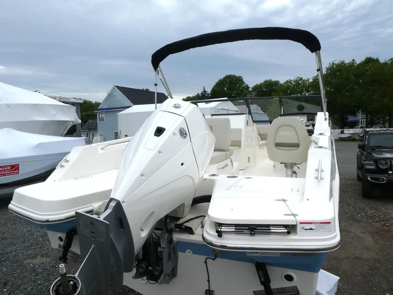Slide: The Image of 2025 Boston Whaler 210 Vantage boat with outboard motor, parked outdoors. - 2