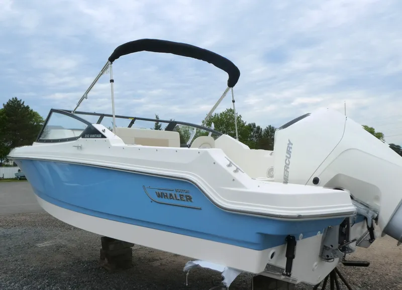 Slide: The Image of 2025 Boston Whaler 210 Vantage boat with blue hull and white interior, docked outdoors. - 3