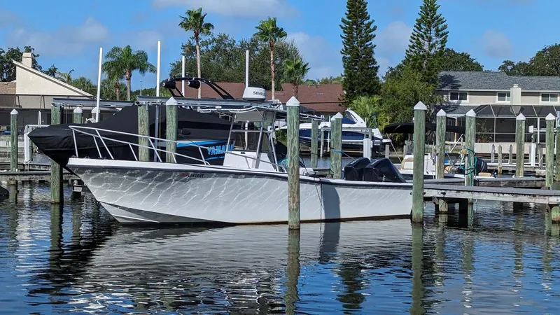 Slide: The Image of 1991 Mako 261 boat docked at a marina with palm trees and houses in the background. - 10