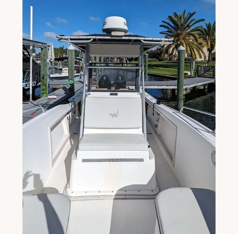 Slide: The Image of 1991 Mako 261 boat docked, featuring center console and seating, under clear blue sky. - 3