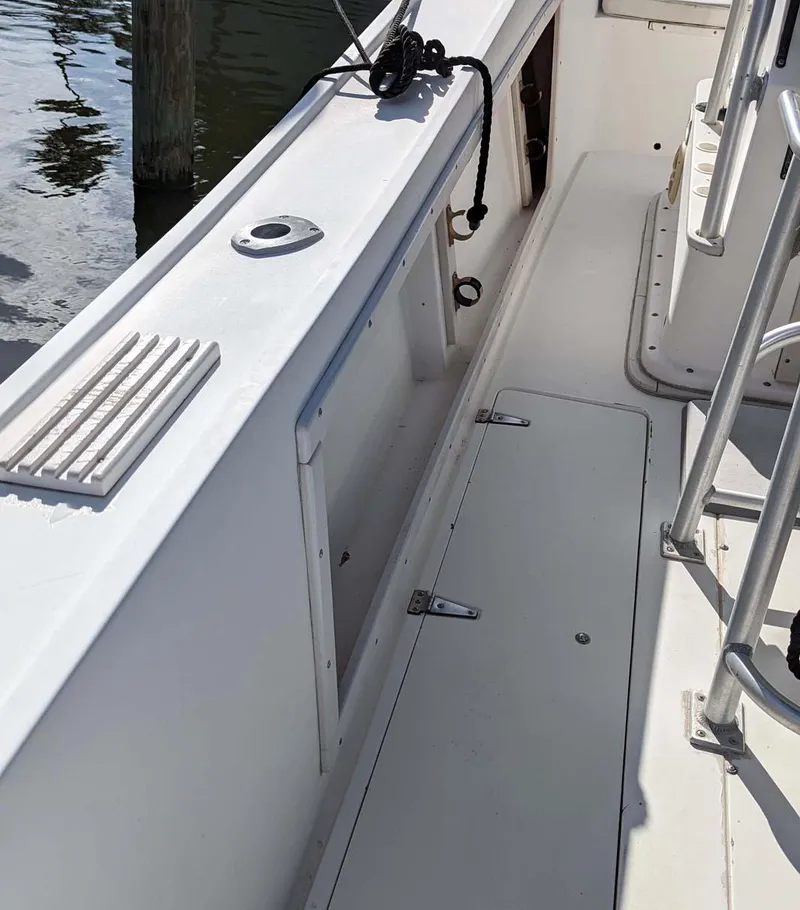 Slide: The Image of 1991 Mako 261 boat deck with storage compartments and railing. - 6