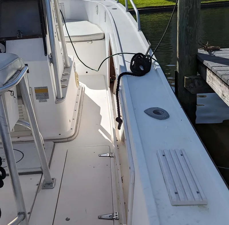 Slide: The Image of 1991 Mako 261 boat interior with white deck and dockside view. - 7