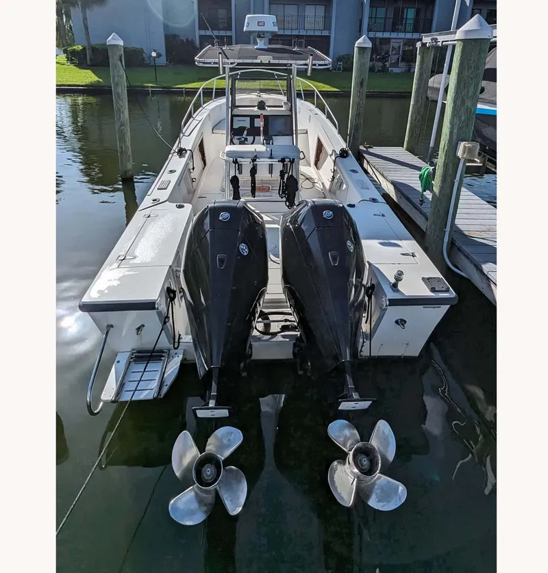 Slide: The Image of 1991 Mako 261 boat with dual outboard motors docked at a marina. - 9