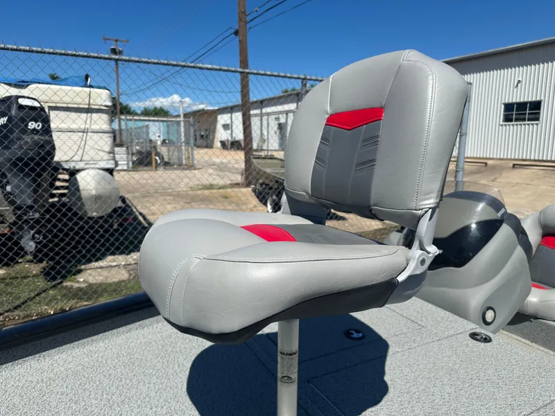 Slide: The Image of 2017 Tracker Pro Team 175 TXW boat seat with red and gray accents, outdoors. - 6