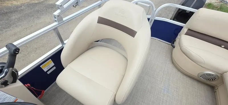 Slide: The Image of 2017 Sun Tracker Party Barge 18 DLX interior with beige seating and steering console. - 9