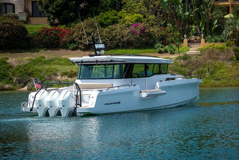 Slide: The Image of 2025 Axopar 45 XC Cross Cabin boat cruising on a scenic waterway. - 10