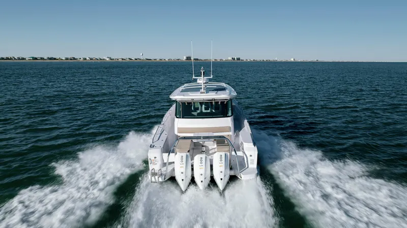 Slide: The Image of 2025 Axopar 45 XC Cross Cabin cruising on open water, rear view. - 6