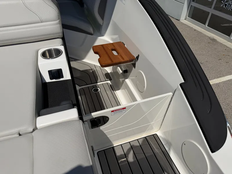 Slide: The Image of The image shows the interior of a 2026 Sea Ray SLX 260 boat with gray upholstery and a wooden table. - 31