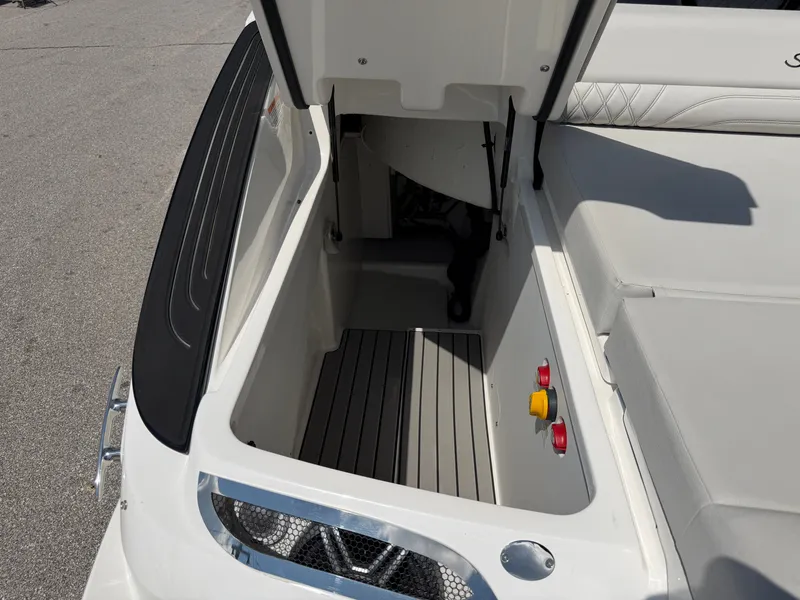 Slide: The Image of Storage compartment at the rear of a Sea Ray SLX 260 boat, with gray flooring and red buttons. - 27